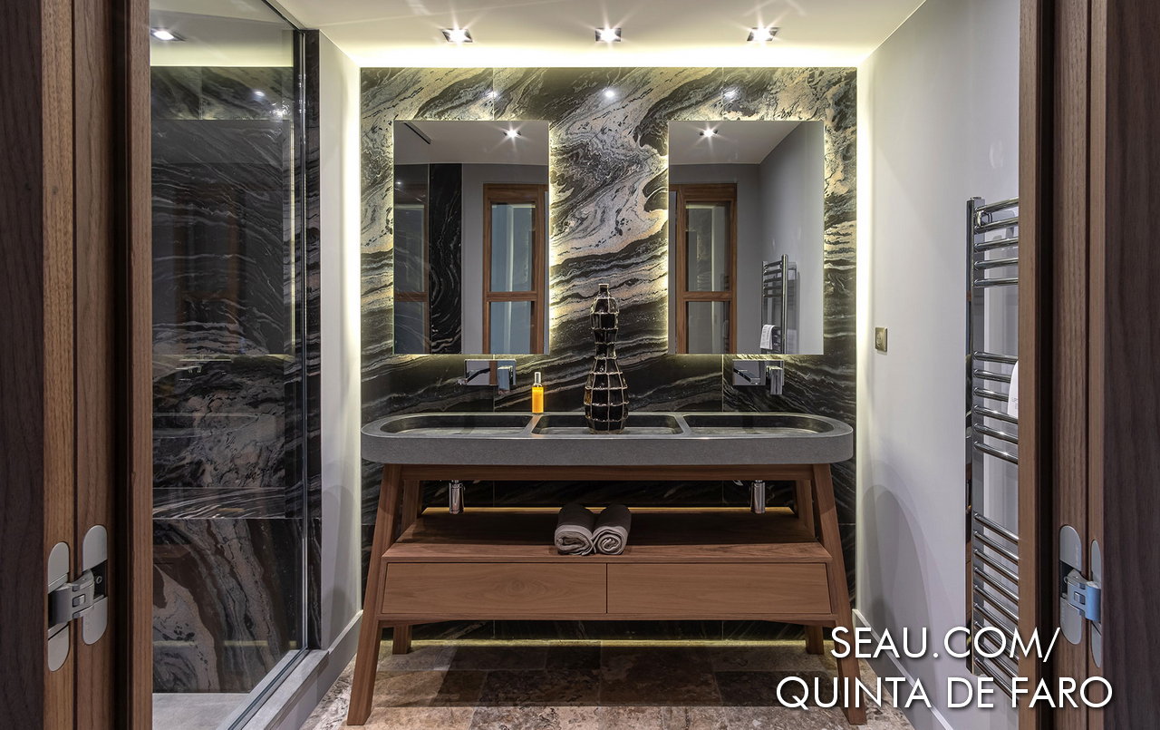 WC avec murs en pierre naturelle et sols en marbre dans les cabines de douche, équipés de double vasque et sèche-serviettes au mur