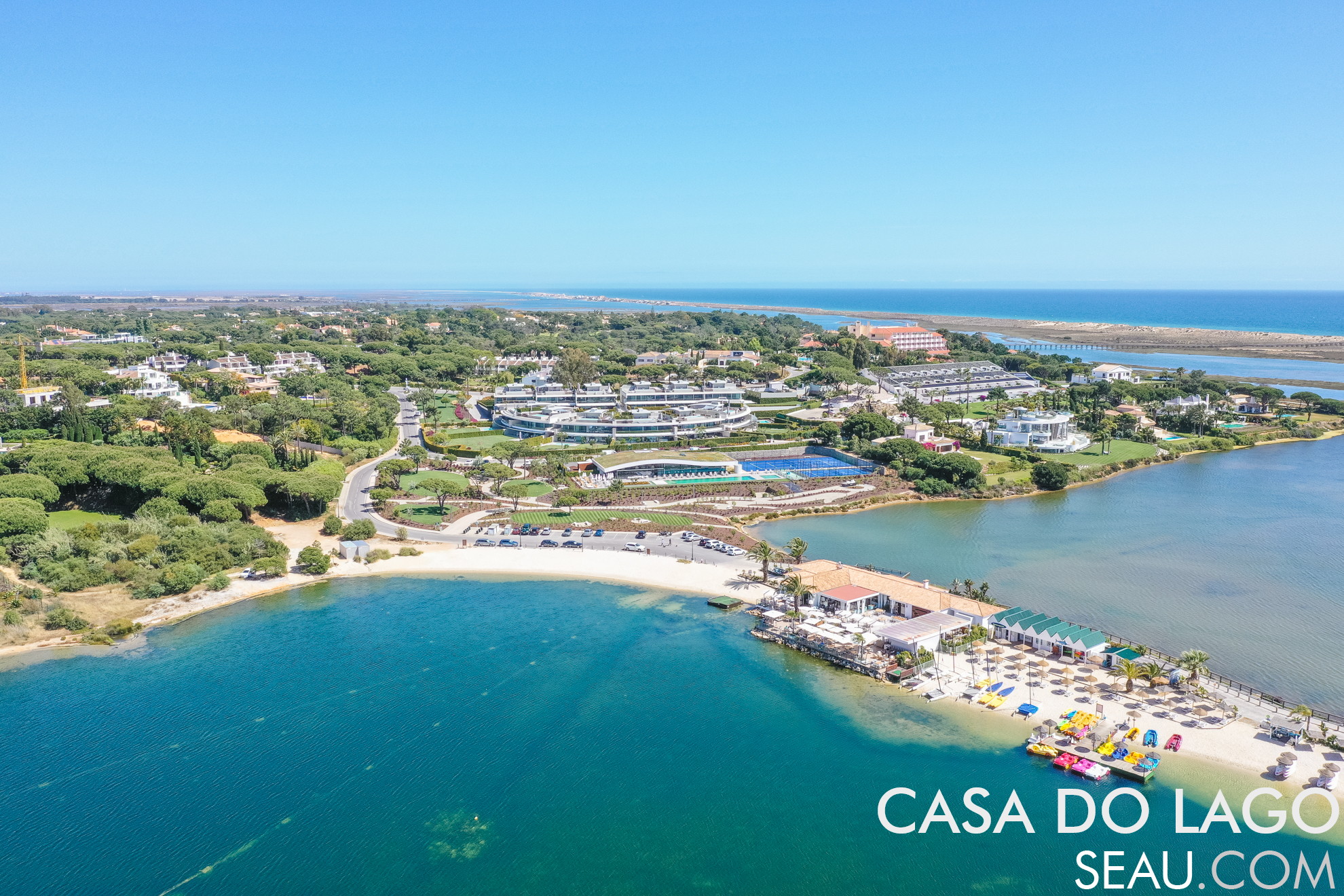 View of the origin of Quinta do Lago. In this image we can see next to the nautical club, the current restaurant Casa do Lago, built from the existing ruin of Casa Velha, an old agricultural house in the original Quinta dos Ramalhos. Behind the slope, in the center of the image is the "Reserva", the luxury development facing the lake.